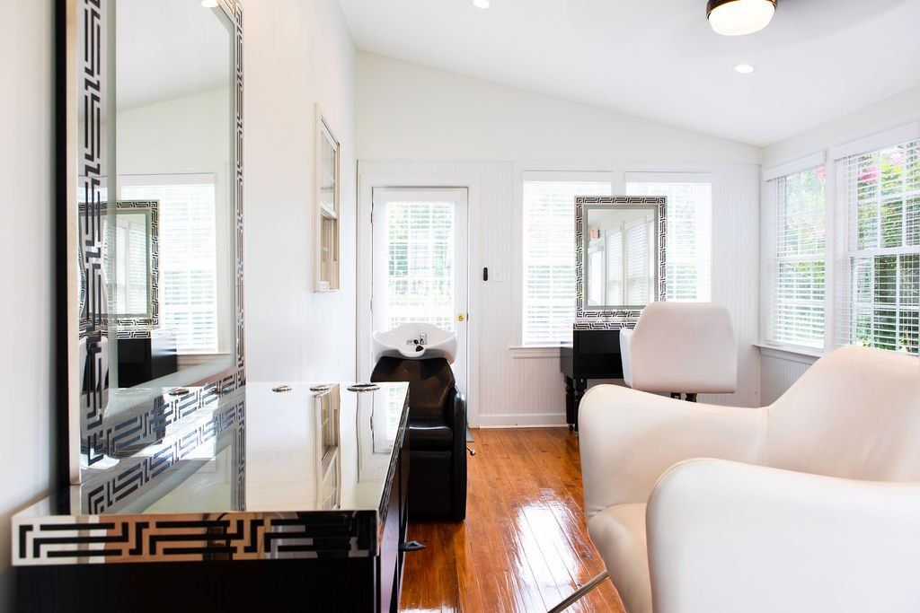 A living room with two white chairs and a mirror