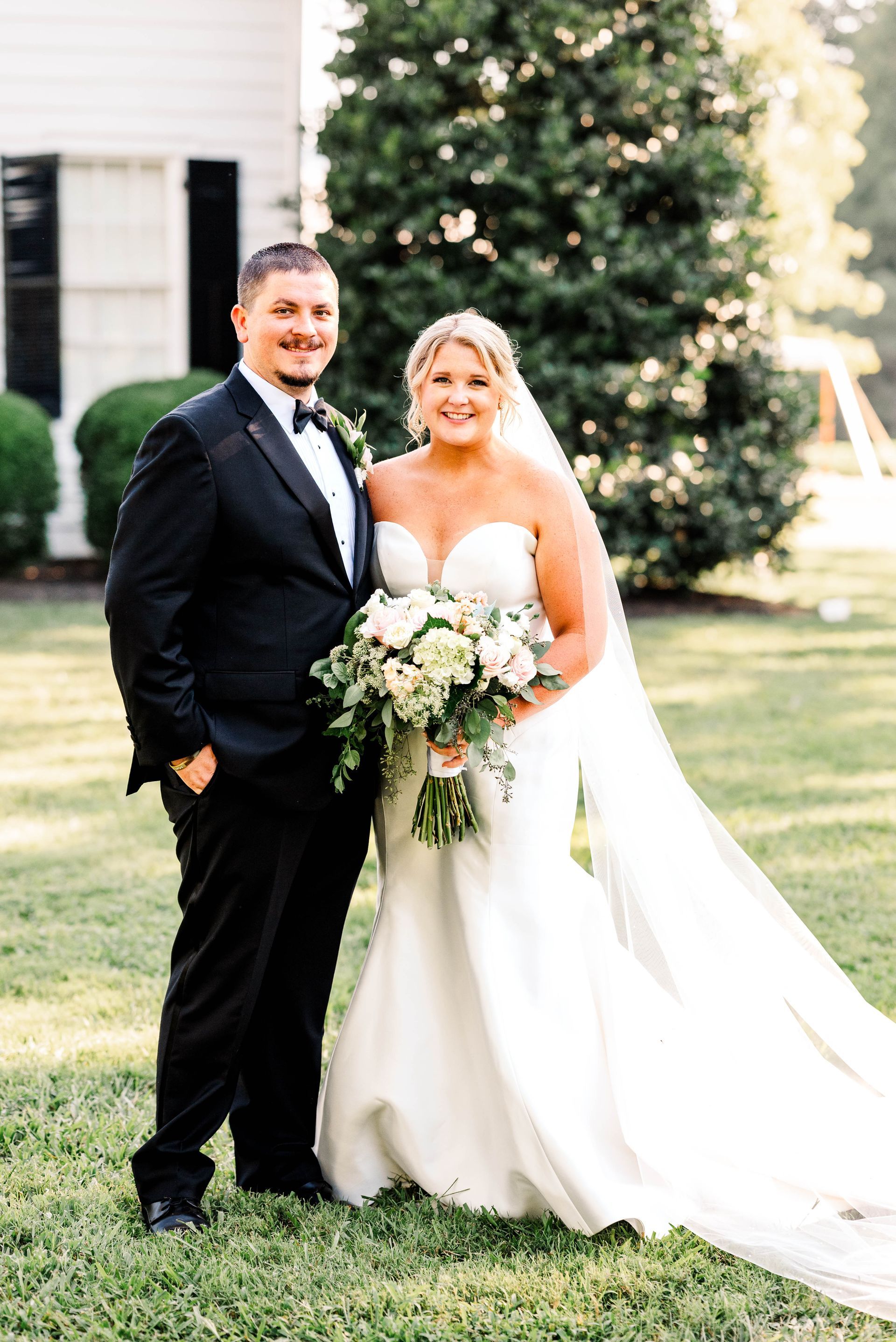 A bride and groom are posing for a picture in front of a white building.