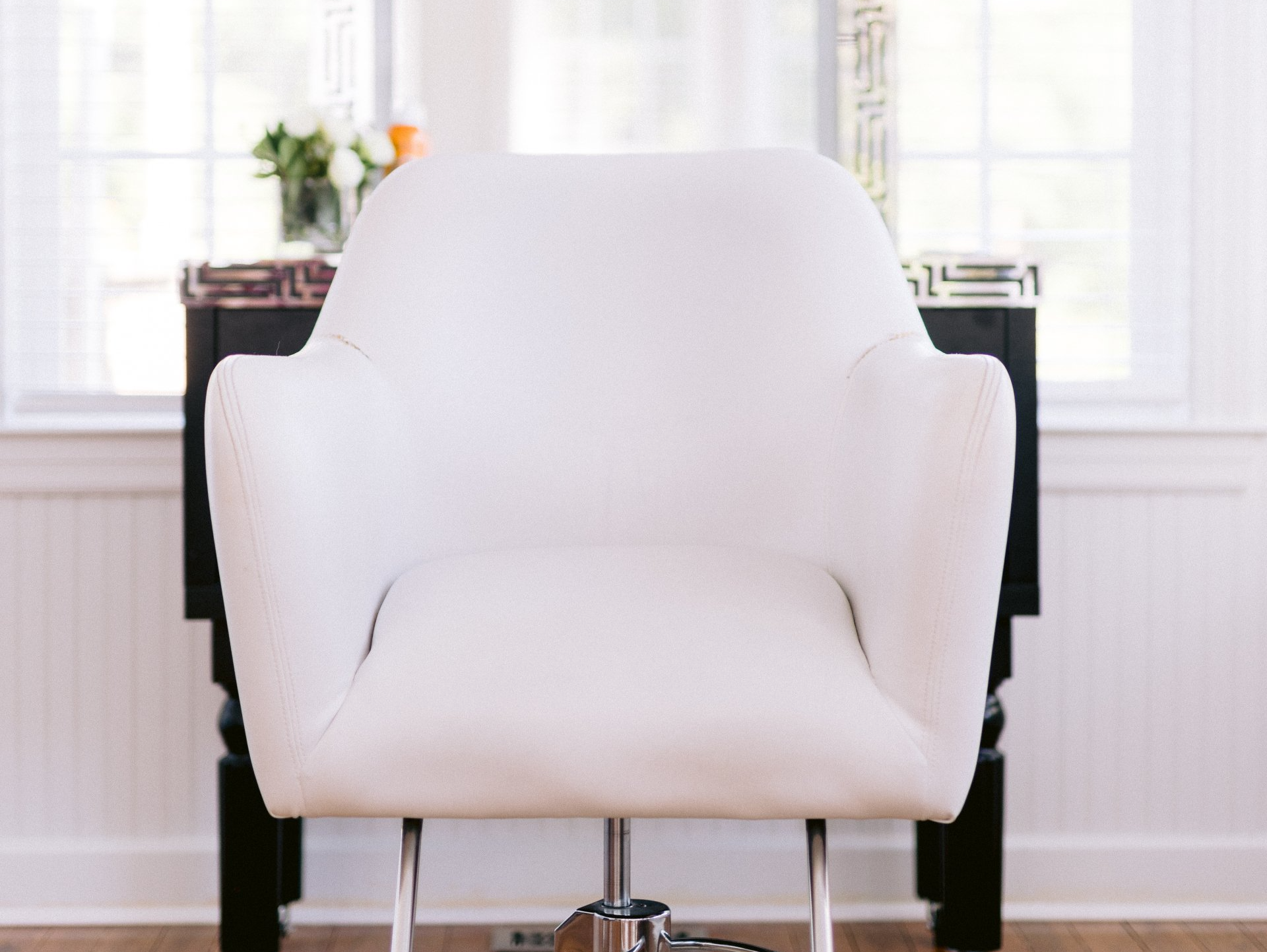 A white chair is sitting in front of a window