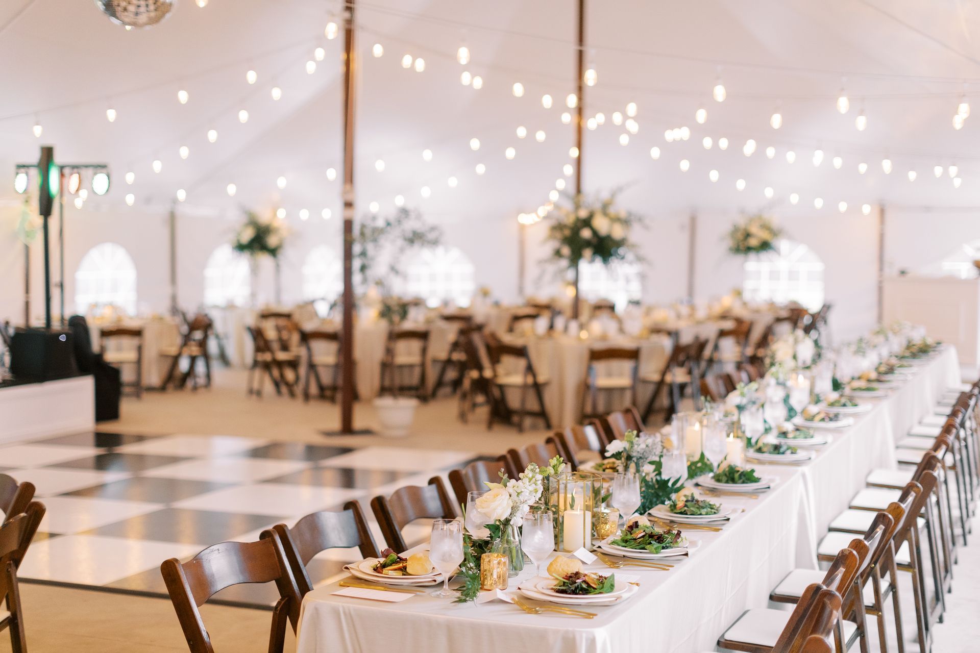 A long table is set for a wedding reception under a tent.