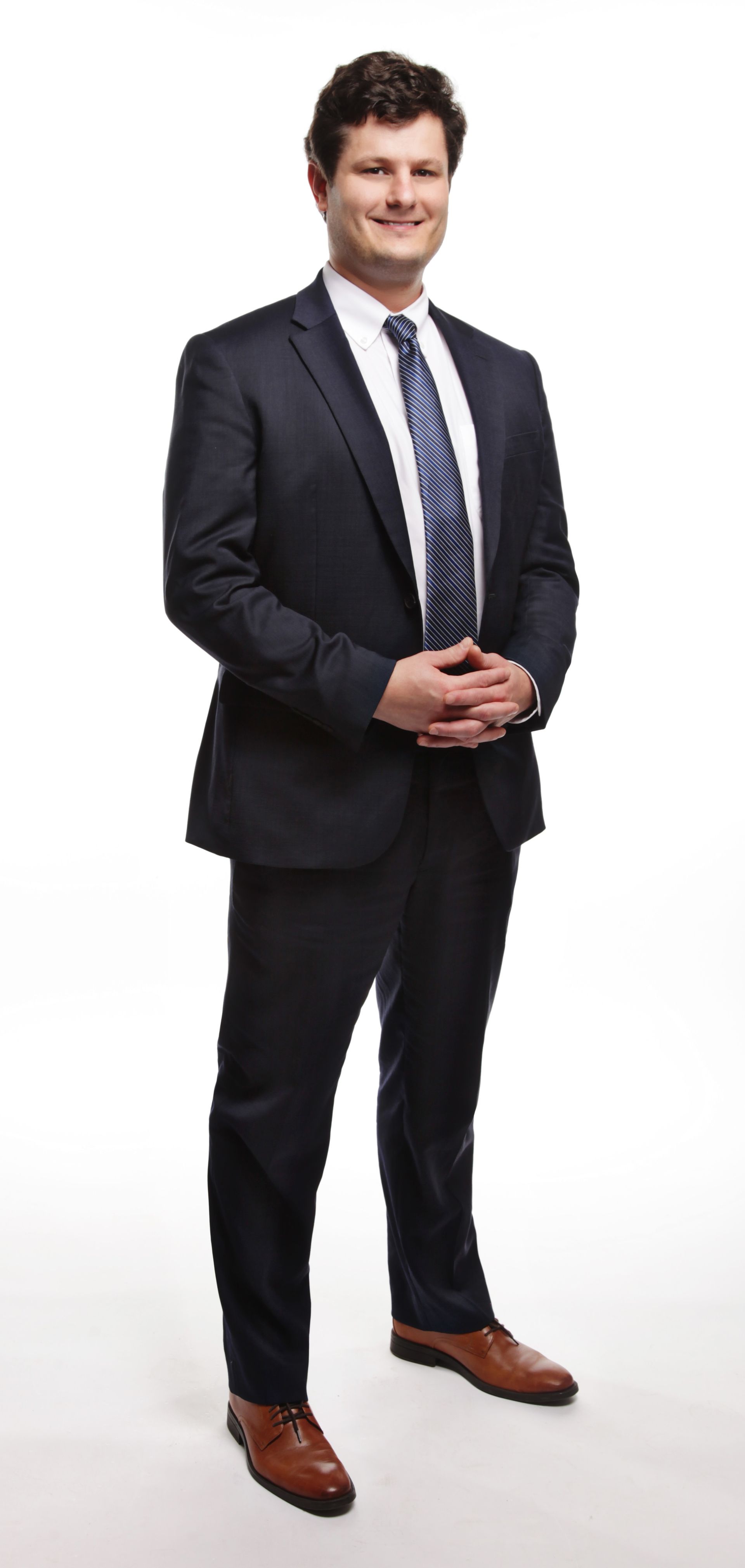 Man in a suit smiles, hands clasped, posing on white background.