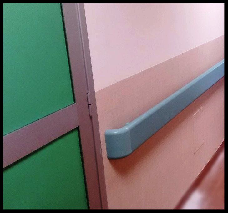Telaio della porta verde e corrimano blu su una parete beige in un corridoio.