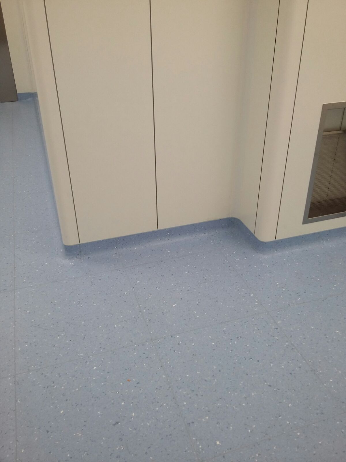Pavimento punteggiato di azzurro chiaro con parete bianca curva e battiscopa blu.