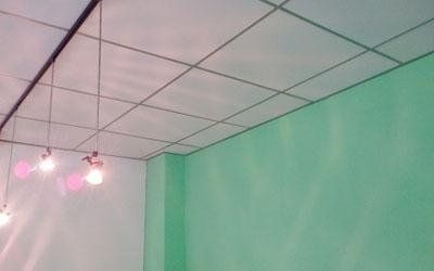 Soffitto con motivo a griglia; pareti verdi e bianche; luci sospese.