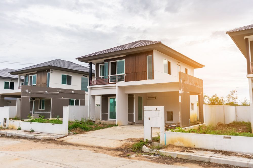 Row of modern houses with white and brown exteriors under a cloudy sky.