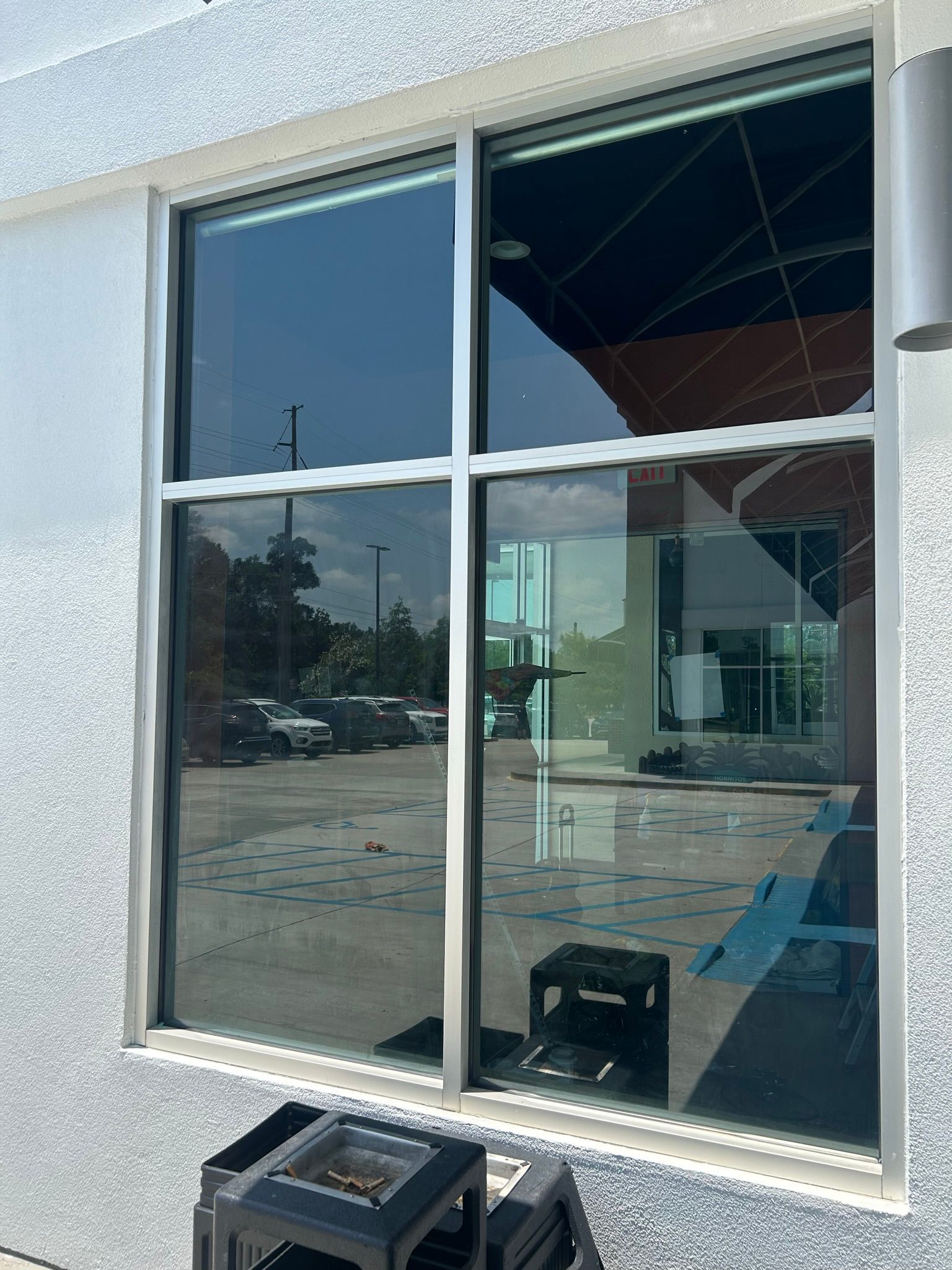Window with dark tint reflects outdoor scene, including a parking lot and a building.