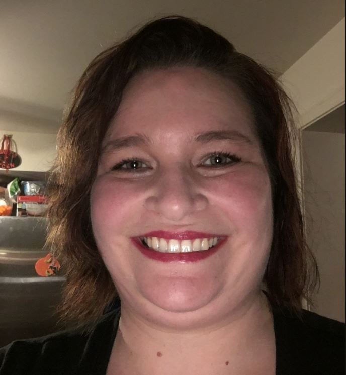 A woman with red lipstick is smiling for the camera