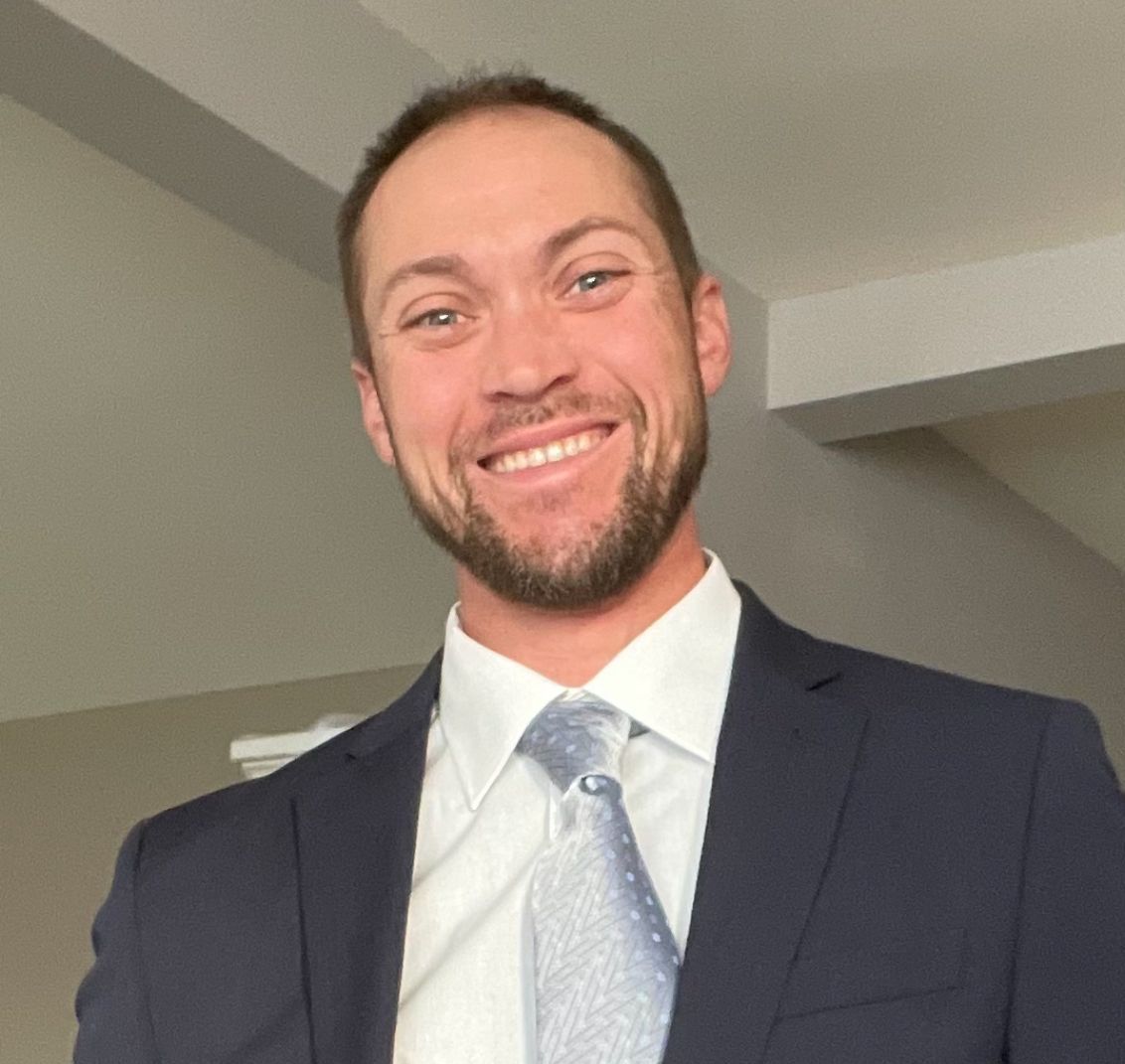 A man in a suit and tie is smiling for the camera