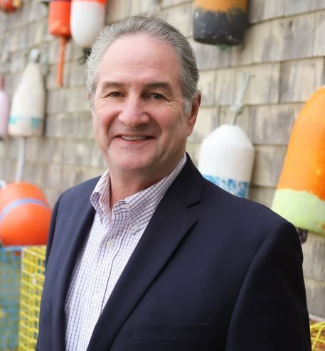 A man in a suit stands in front of a wall of buoys