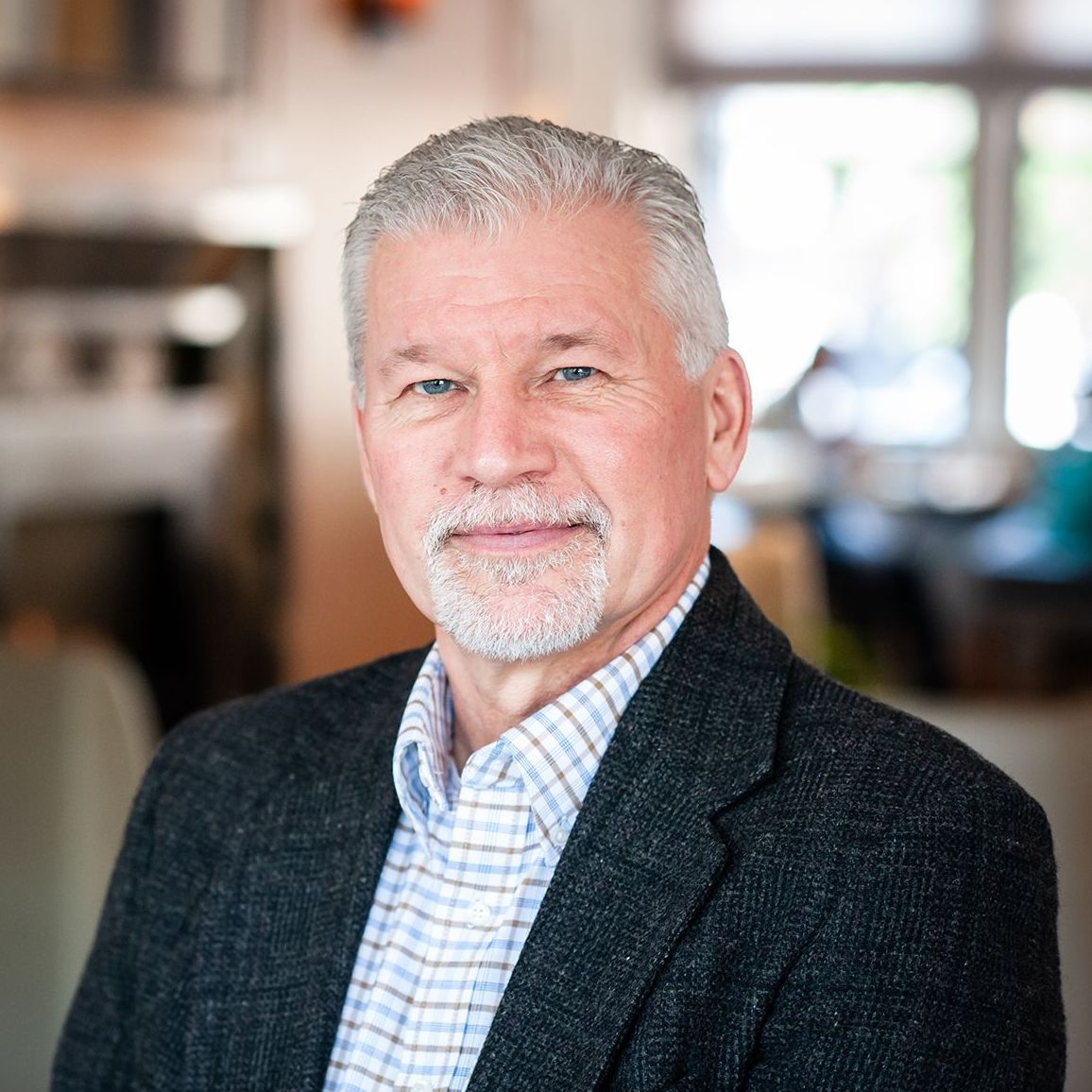 A man with a beard is wearing a suit and a plaid shirt.