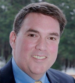 A man in a suit and tie is smiling for the camera.