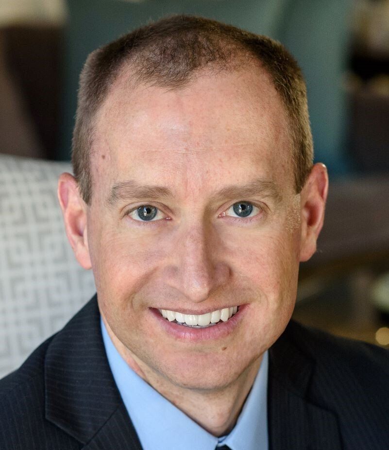 A man in a suit and tie is smiling for the camera.