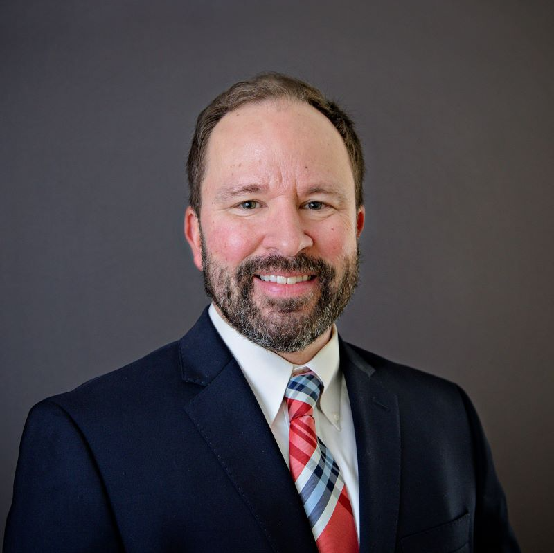 A man in a suit and tie is smiling for the camera.