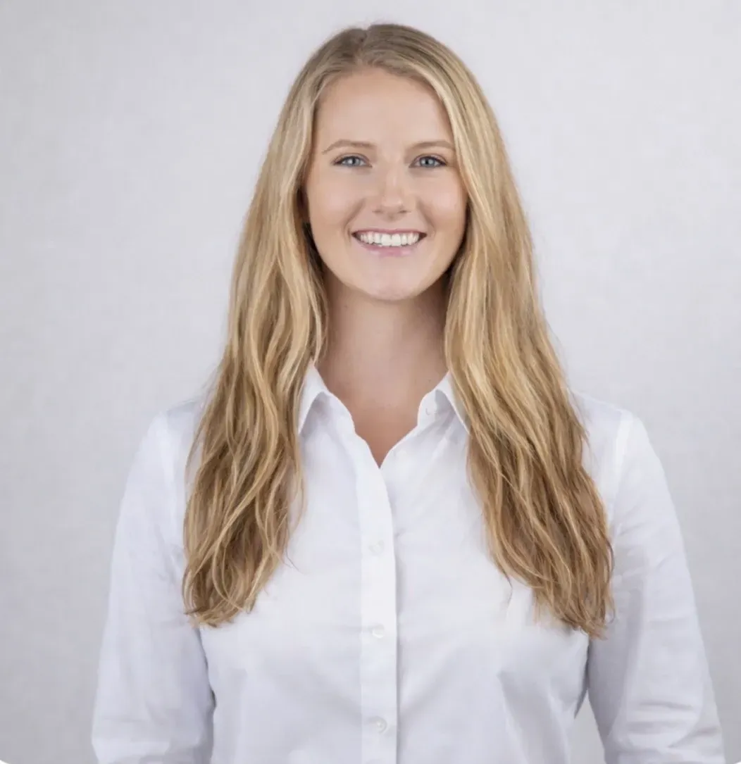 Smiling blonde woman in a white shirt against a light gray background