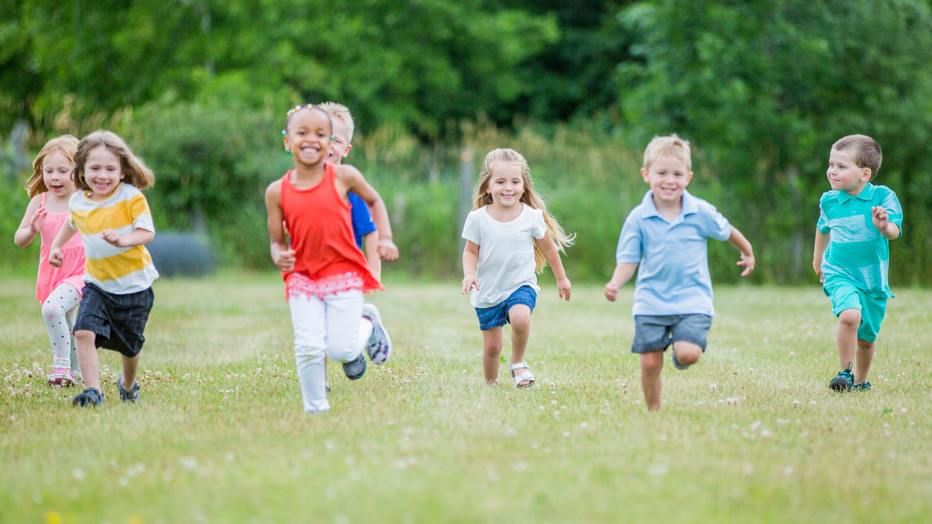 Children running and smiling in a grassy field.