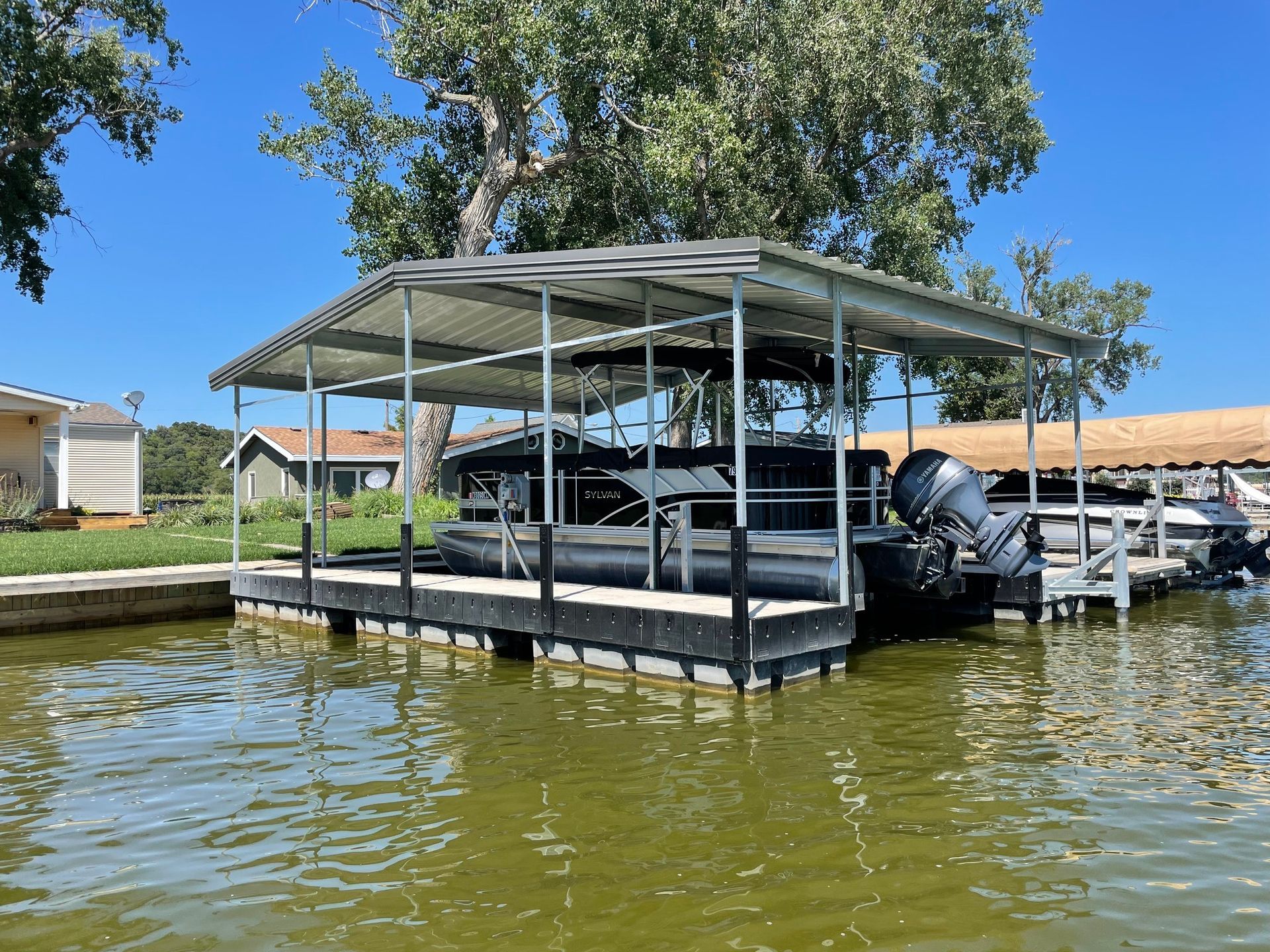Covered dock with chairs on a flooded lake shore under a blue sky