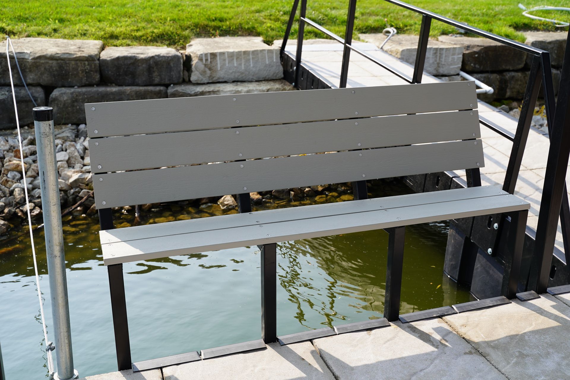 Gray bench beside a small waterway with metal railings and stone steps nearby