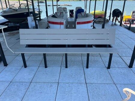White bench on tiled patio beside boats and a waterfront dock