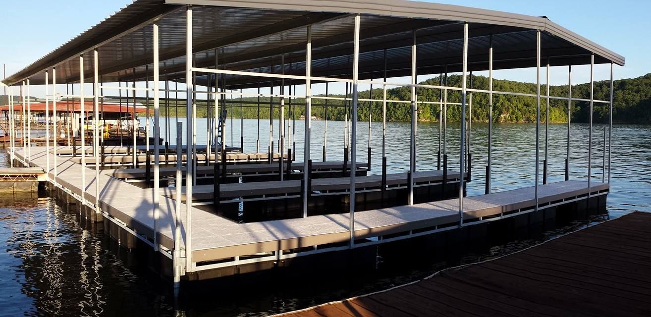 Covered dock on calm water with boat slips and a wooden platform at sunset