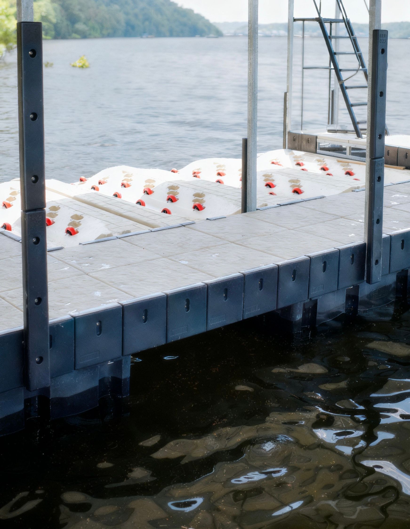 White buoys or foam floating beside a dock on a lake, with metal railings and water in the foreground