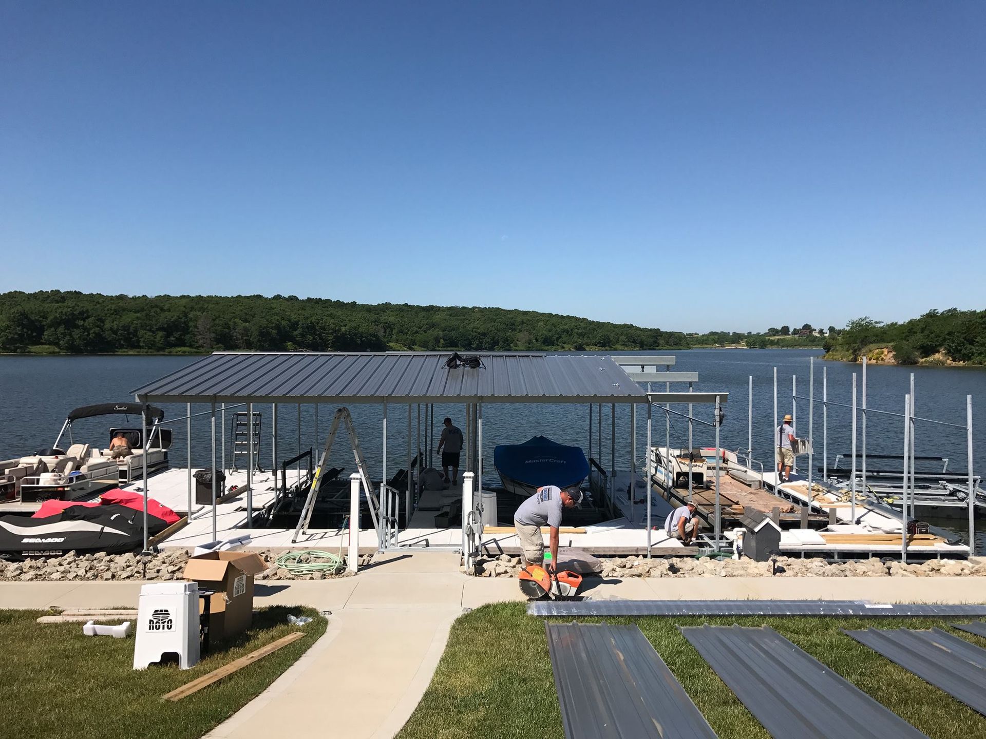 Dock with boats and a lakeside canopy under a clear blue sky
