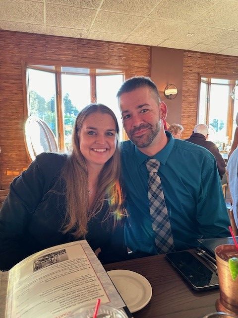 A man and a woman are posing for a picture at a restaurant.