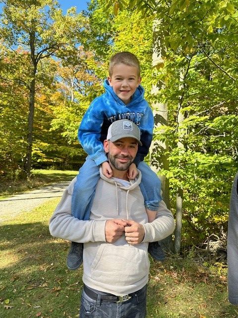A man is carrying a little boy on his shoulders