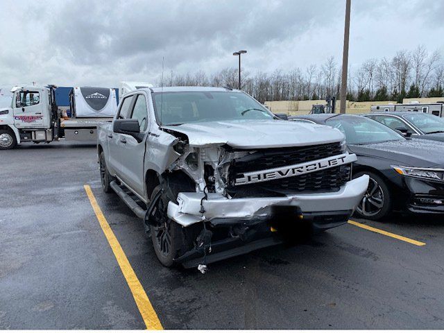 A silver chevrolet truck is damaged in a parking lot.