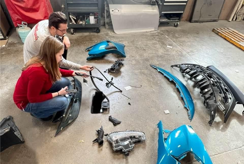 A man and a woman are working on a car in a garage.