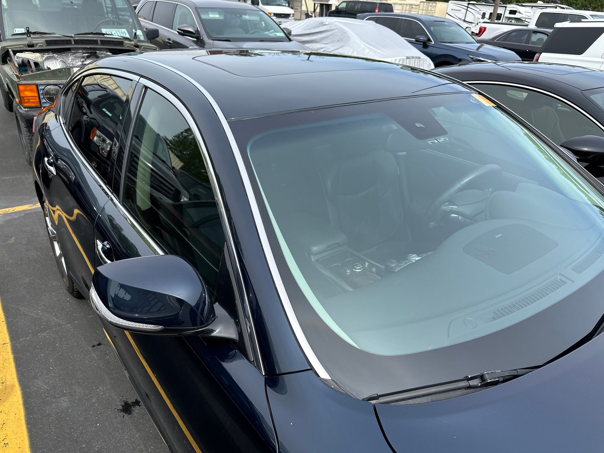 Black sedan parked in a crowded lot, viewed from above with other cars nearby