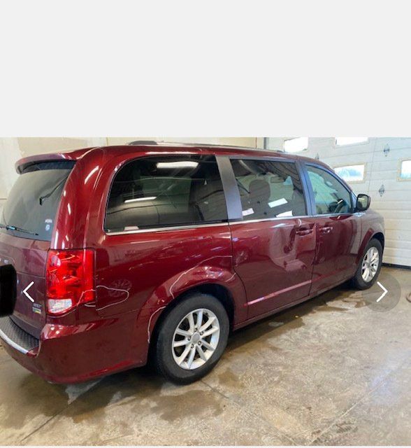 A red minivan is parked in front of a garage door