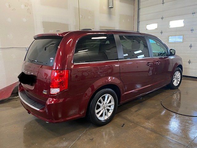 A red minivan is parked in a garage next to a garage door.