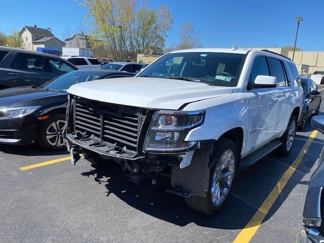 A white suv with a damaged front end is parked in a parking lot.