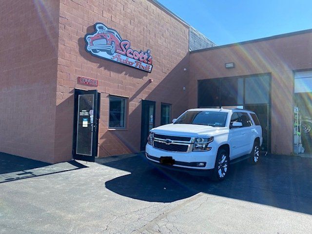 A white suv is parked in front of a scott automotive building