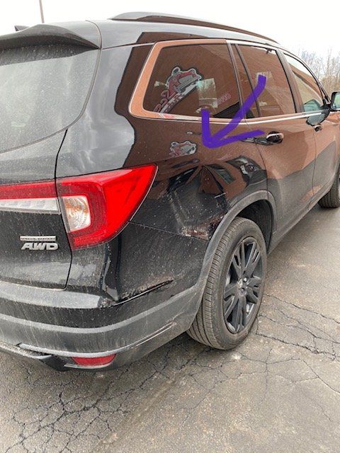 A black honda pilot is parked on the side of the road.
