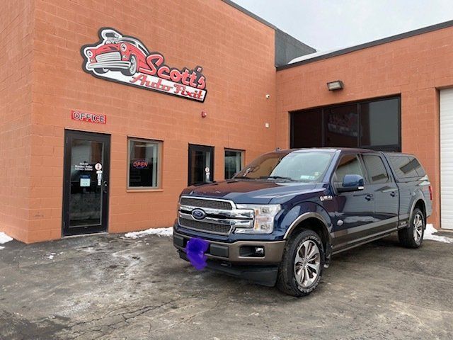 A blue ford truck is parked in front of scott 's auto repair shop