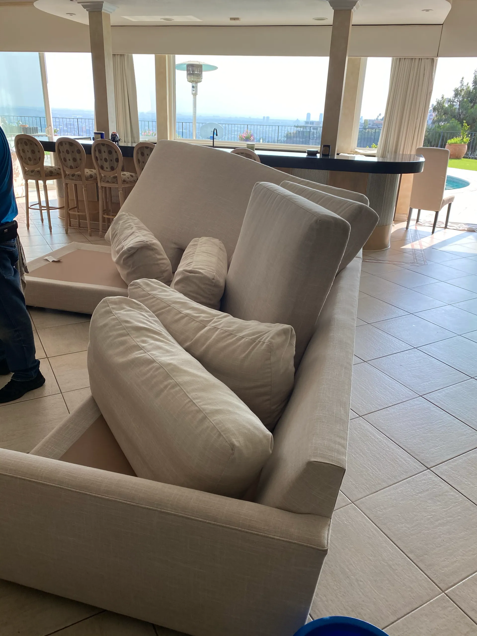 Cream upholstered sofa with pillows in a bright indoor patio overlooking the sea.