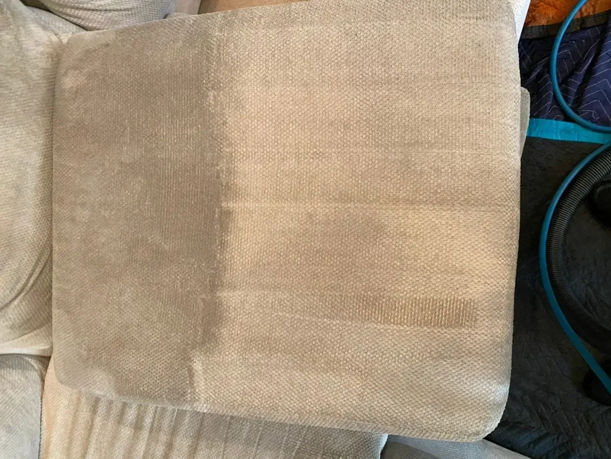 Beige square cushion on a dark sofa with teal accents nearby