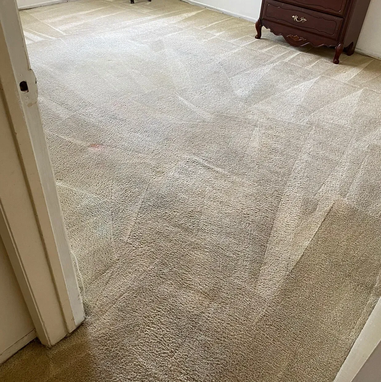 Carpeted bedroom doorway with beige carpet and a wooden dresser in the corner