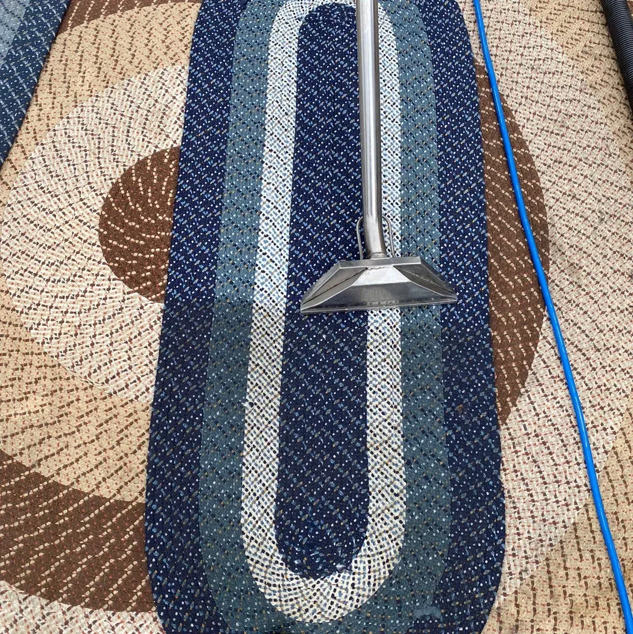Metal tool on patterned woven rug with blue, tan, and brown stripes