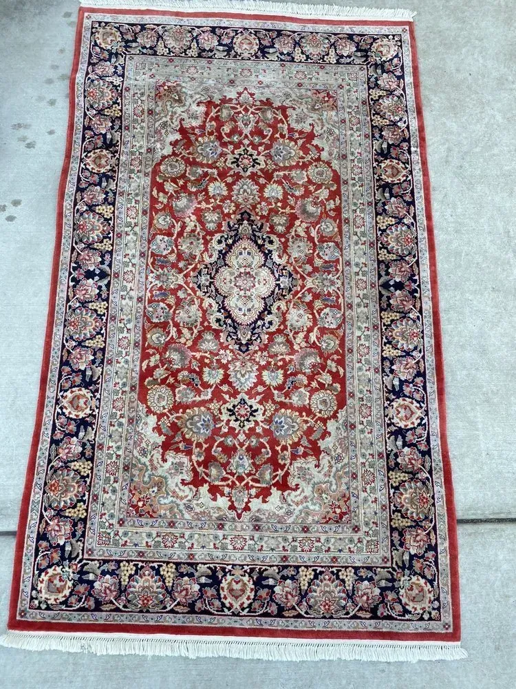Red and cream Persian-style rug with ornate floral medallion and border on a light floor
