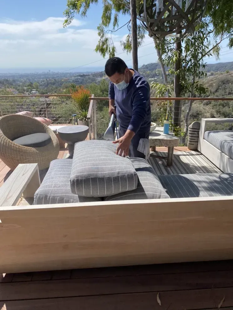 Person arranging cushions on an outdoor deck lounge with scenic valley view.