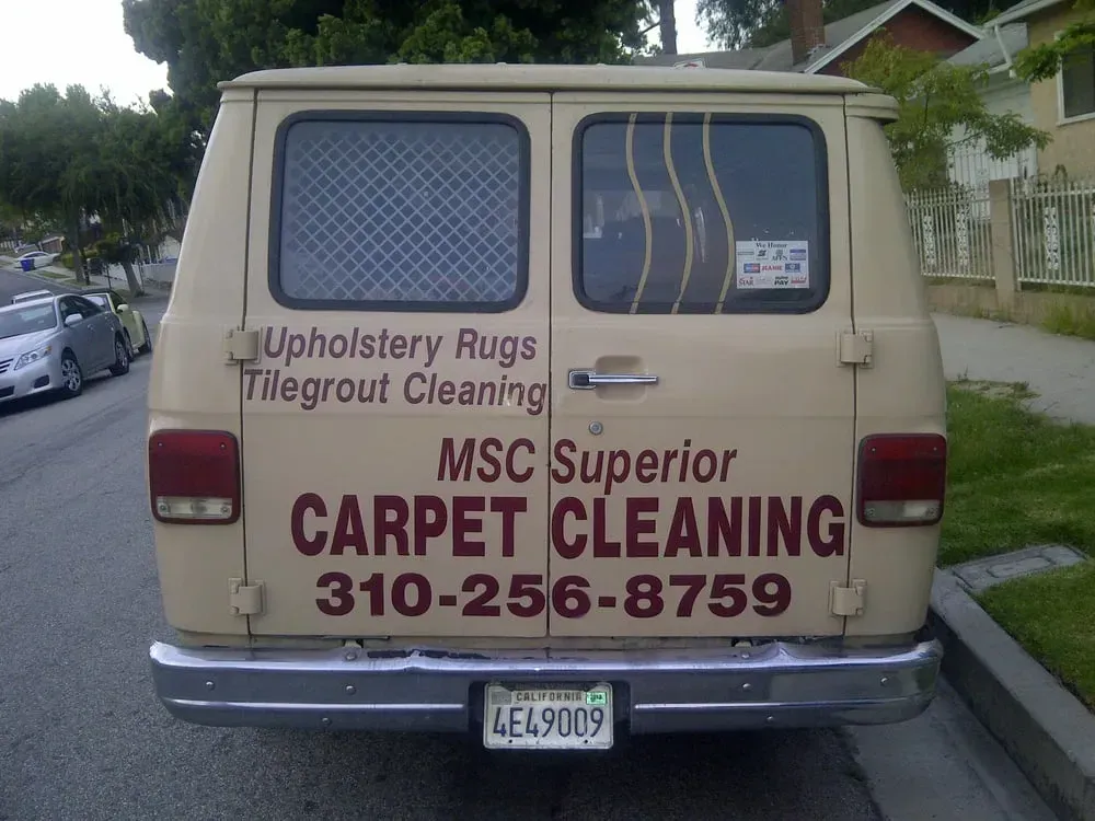 Beige van with sign for MSC Superior Carpet Cleaning parked on a residential street