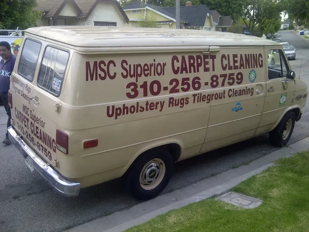 Beige carpet cleaning van parked on a street, with company name and phone number on the side