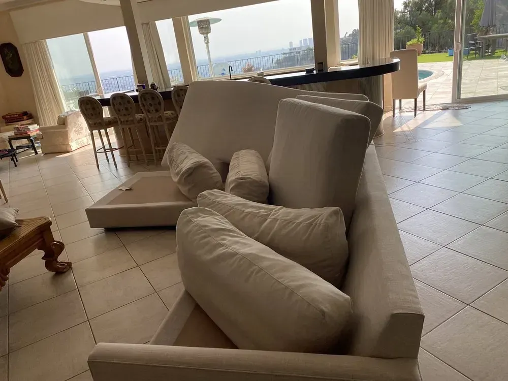 Bright living room with beige sofas, tiled floor, and ocean view through large windows