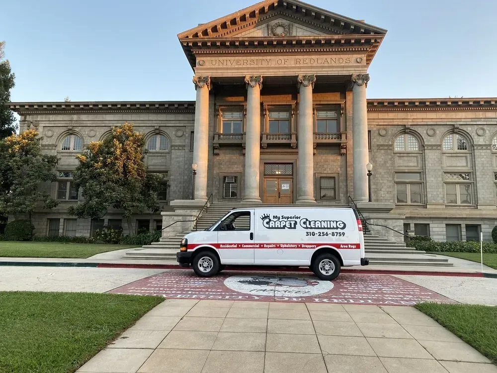 White van parked in front of a grand neoclassical building with columns and a red-tiled roof.