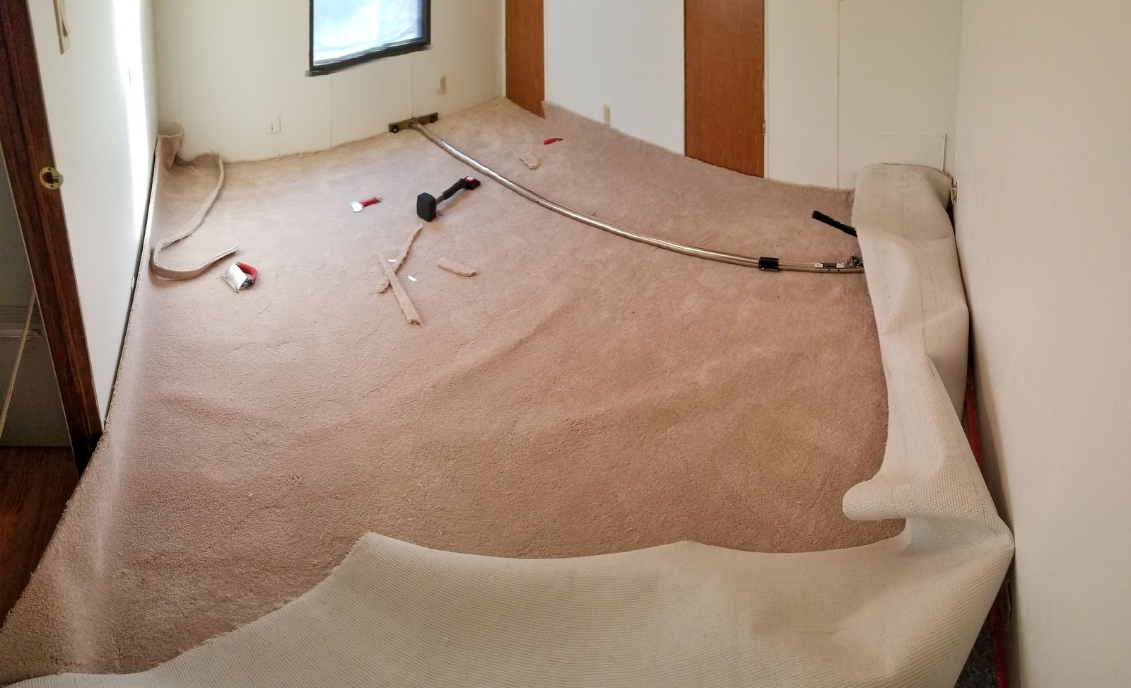 Unmade bed with wrinkled white sheets and scattered cords in a small bedroom.