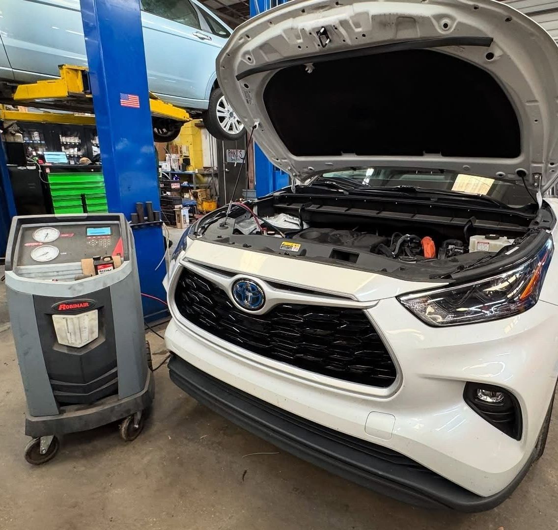 White Subaru SUV with hood open in a service bay beside a maintenance cart and lift