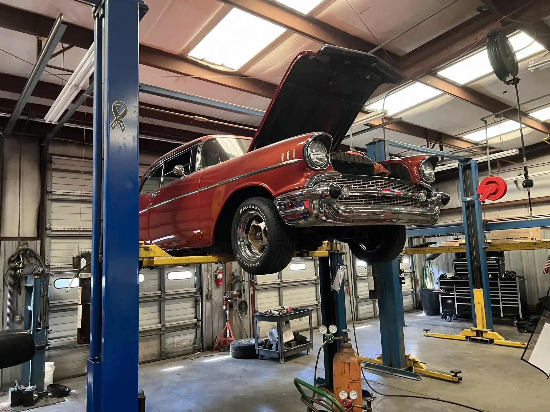 Red classic car raised on a lift in an auto repair shop with hood open