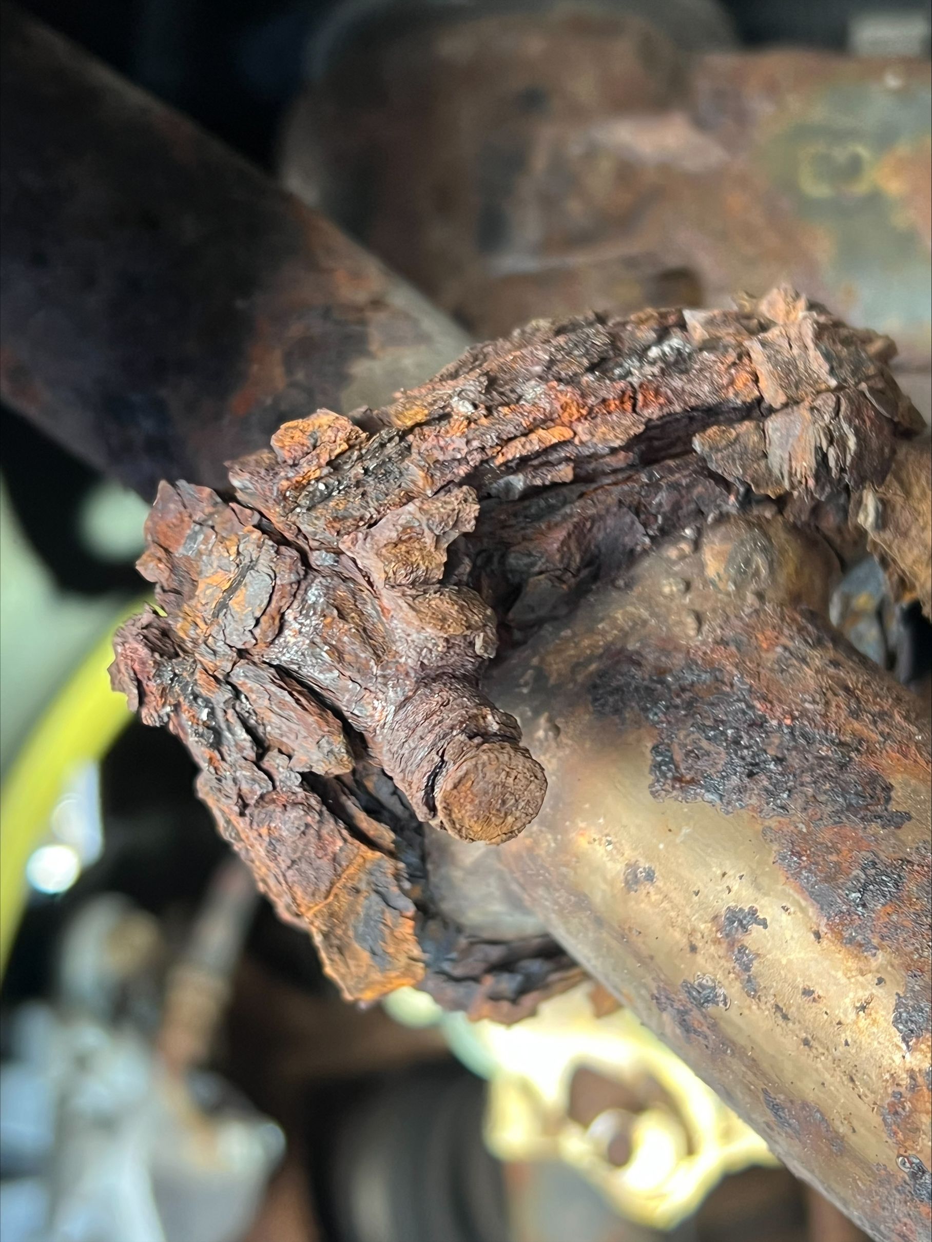 Severely rusted metal joint with flaking corrosion on a pipe or frame.
